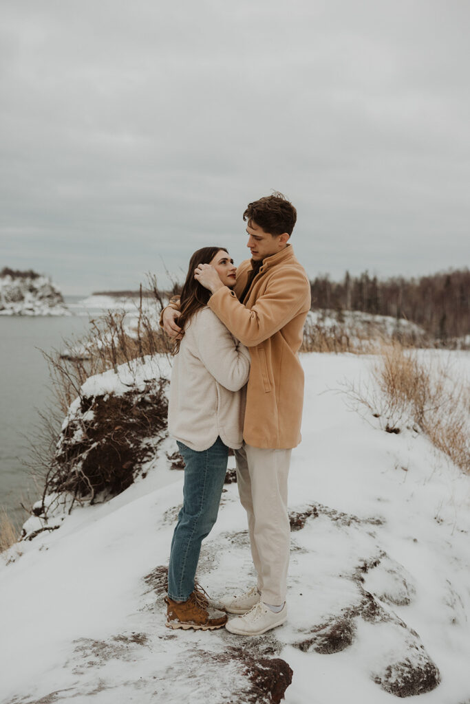 Woman nestles into man as he gingerly tucks her hair behind her ear