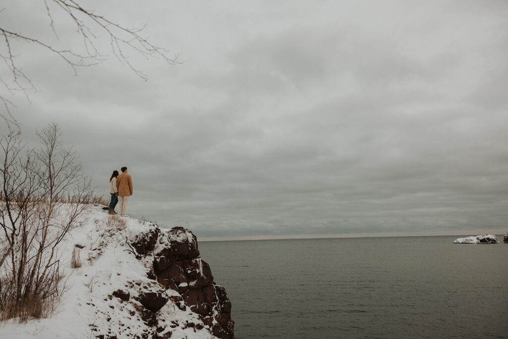 Man and woman stand on Black Beach overlooking the North Shore of Minnesota