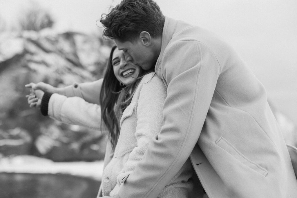 Man in peacoat kisses fiance's cheek in North Shore engagement photoshoot