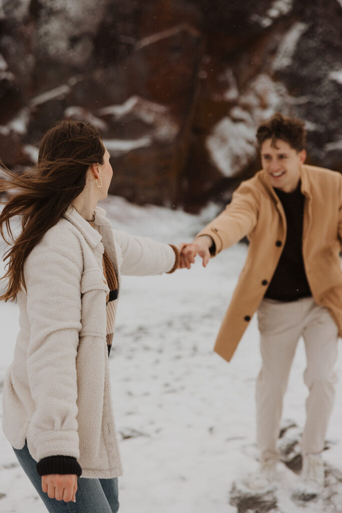 Engaged couple reaches for each other during Black Beach engagement