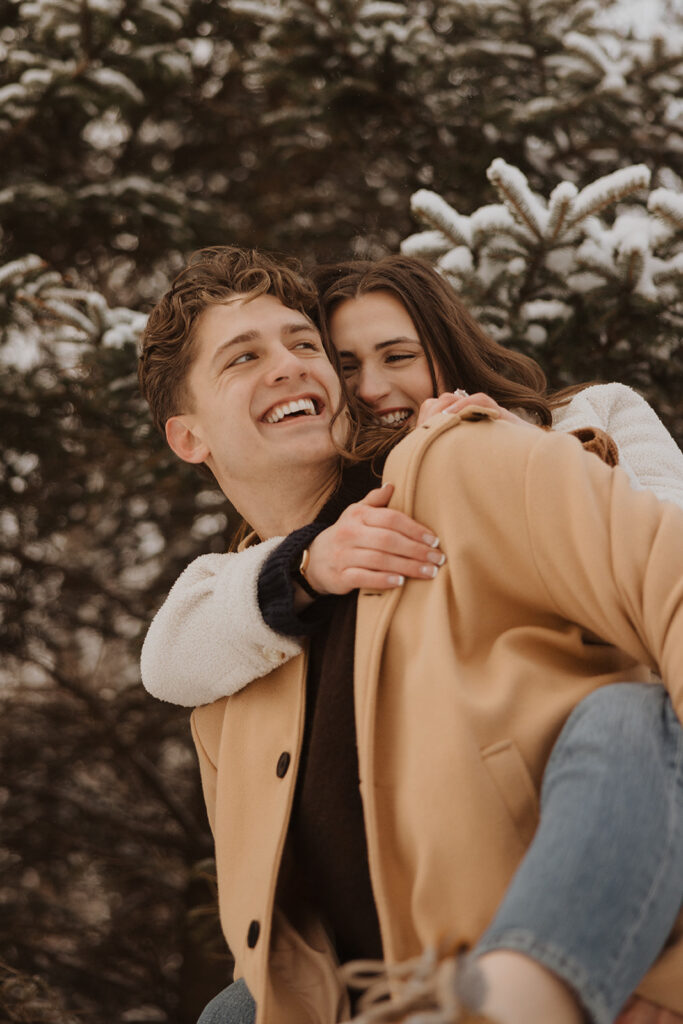 Man gives woman a piggyback ride during Black Beach engagement photoshoot