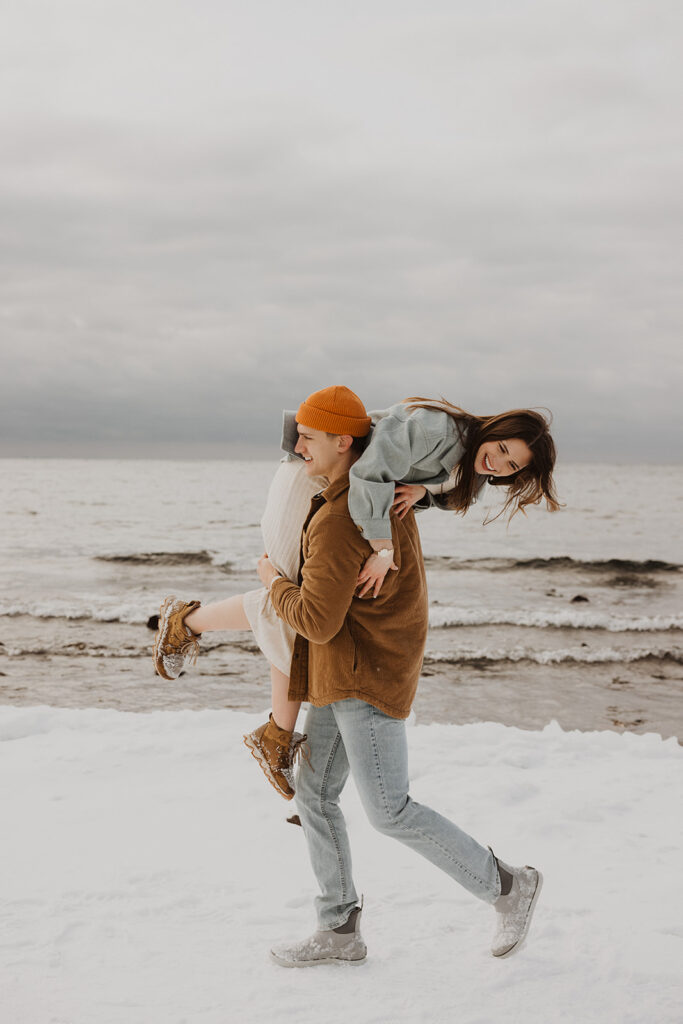 Man picks up his fiance and carries across Black Beach in North Shore, Minnesota