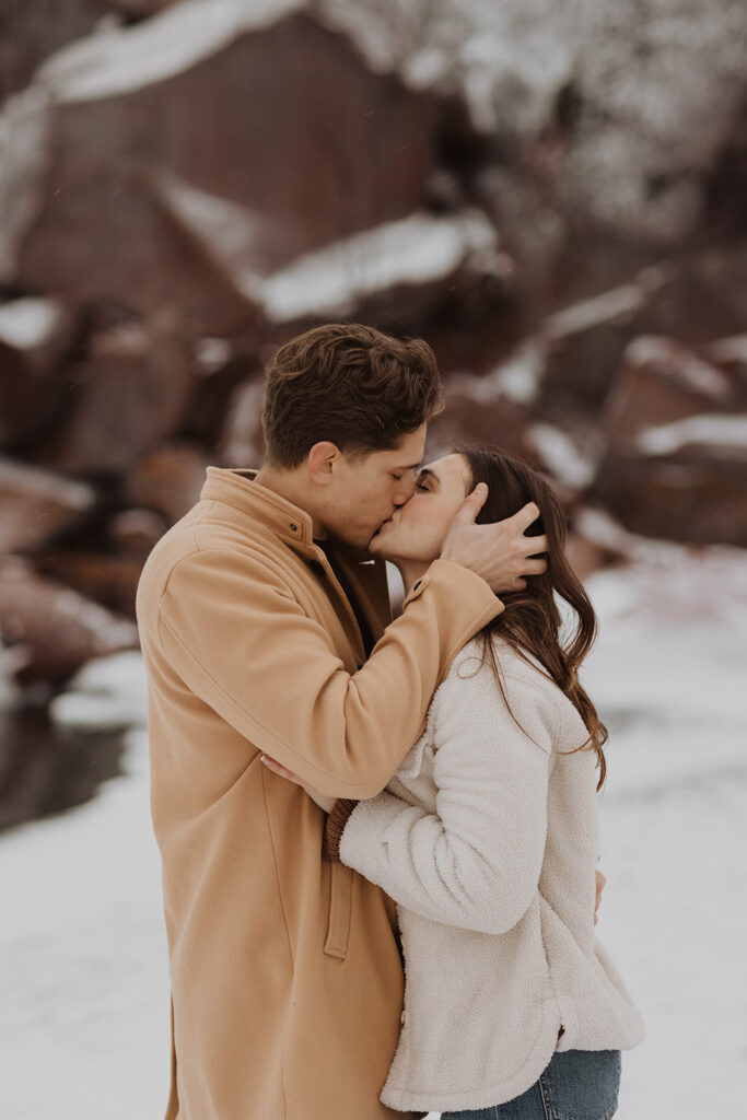 Man holds woman's head while he kisses her gently on Black Beach