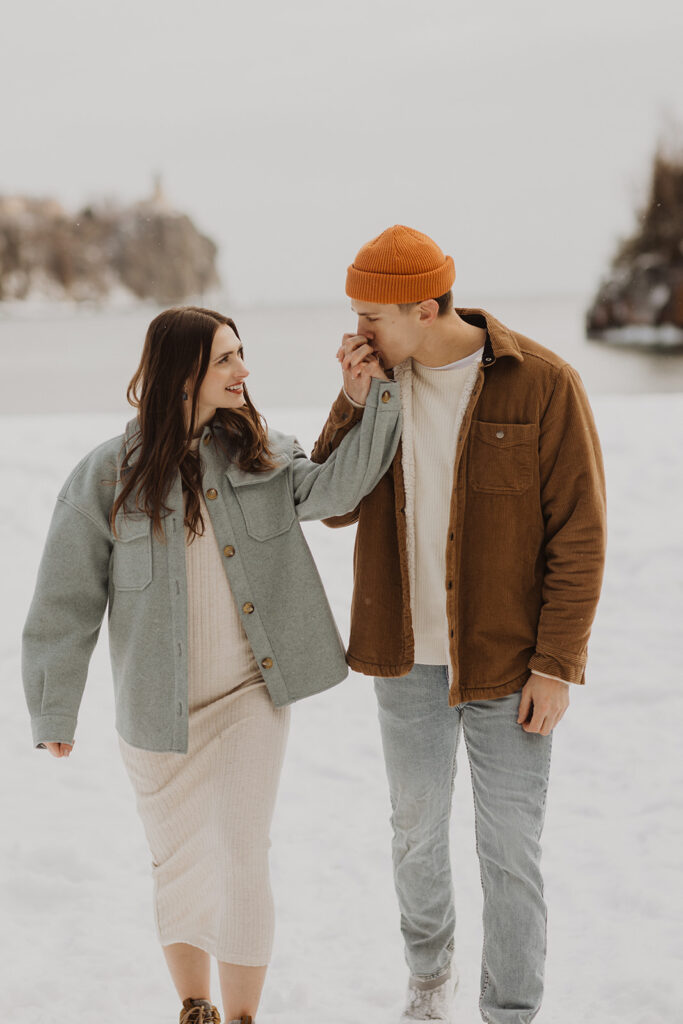 Man kisses woman's cold hands during winter engagement session in Minnesota