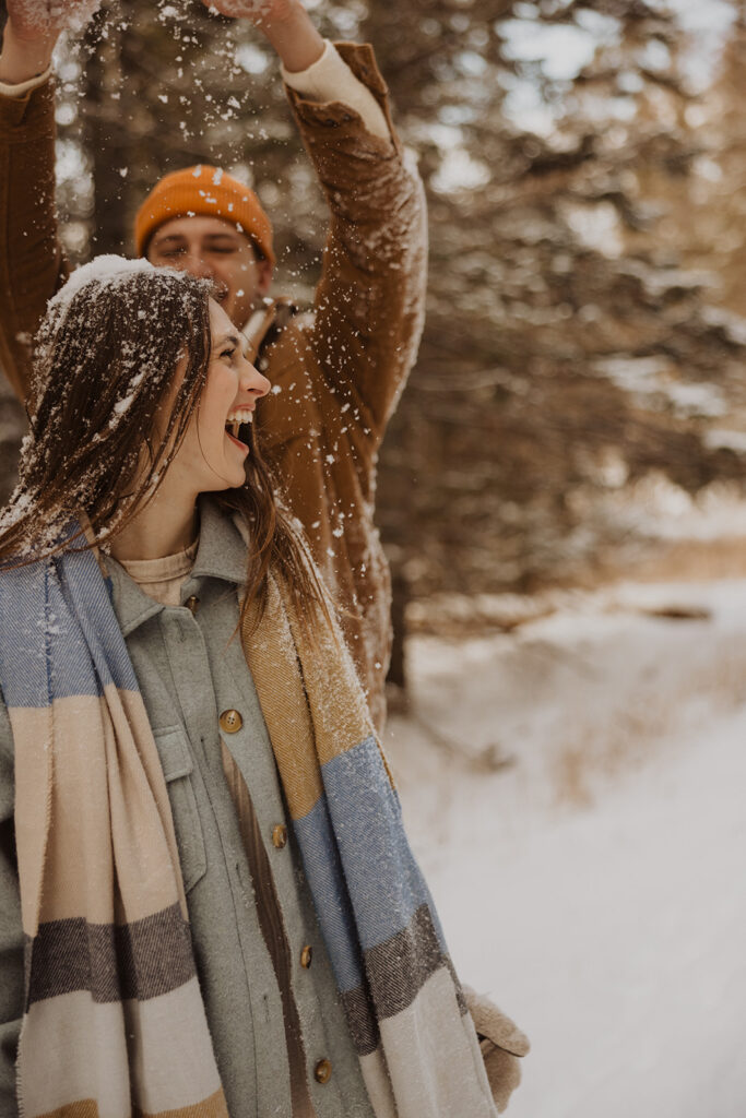 Adventurous couple plays in the snow during winter engagement session in Minnesota