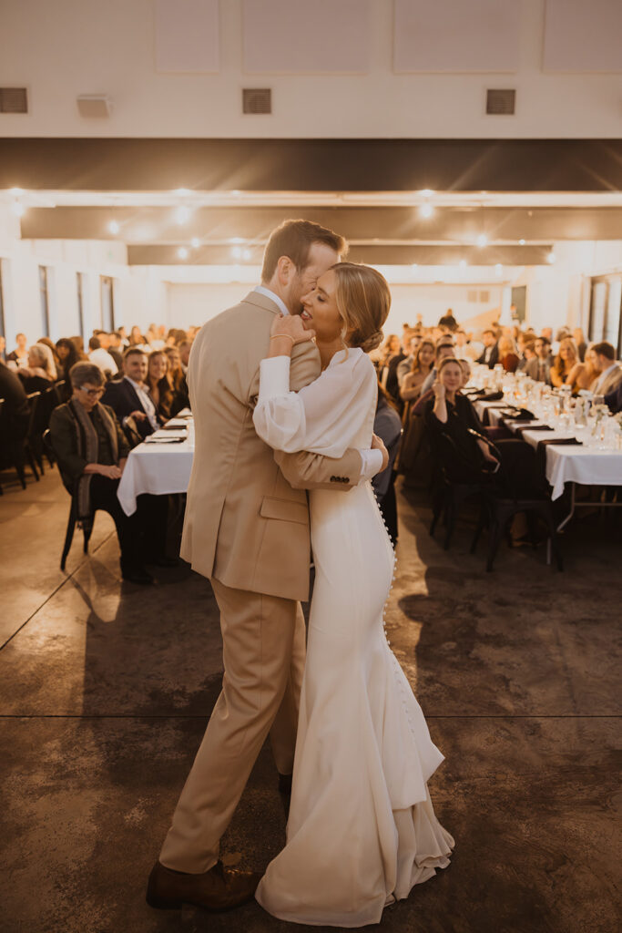 Bride and groom embrace during first dance at winter wedding venue