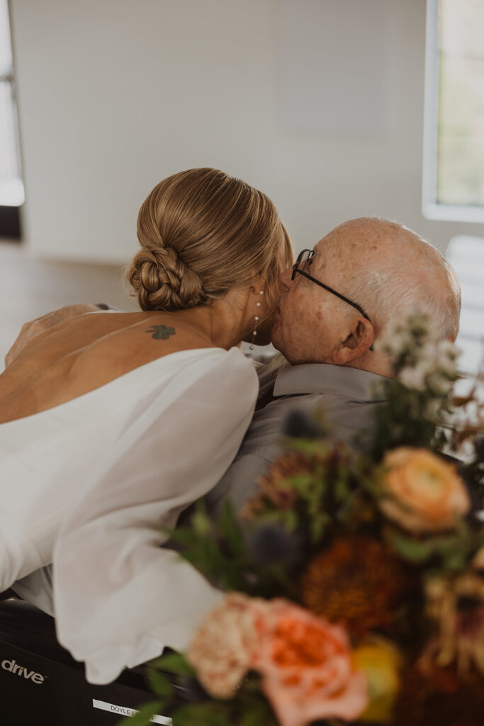 Grandpa kisses bride's cheek as she leans down to embrace him