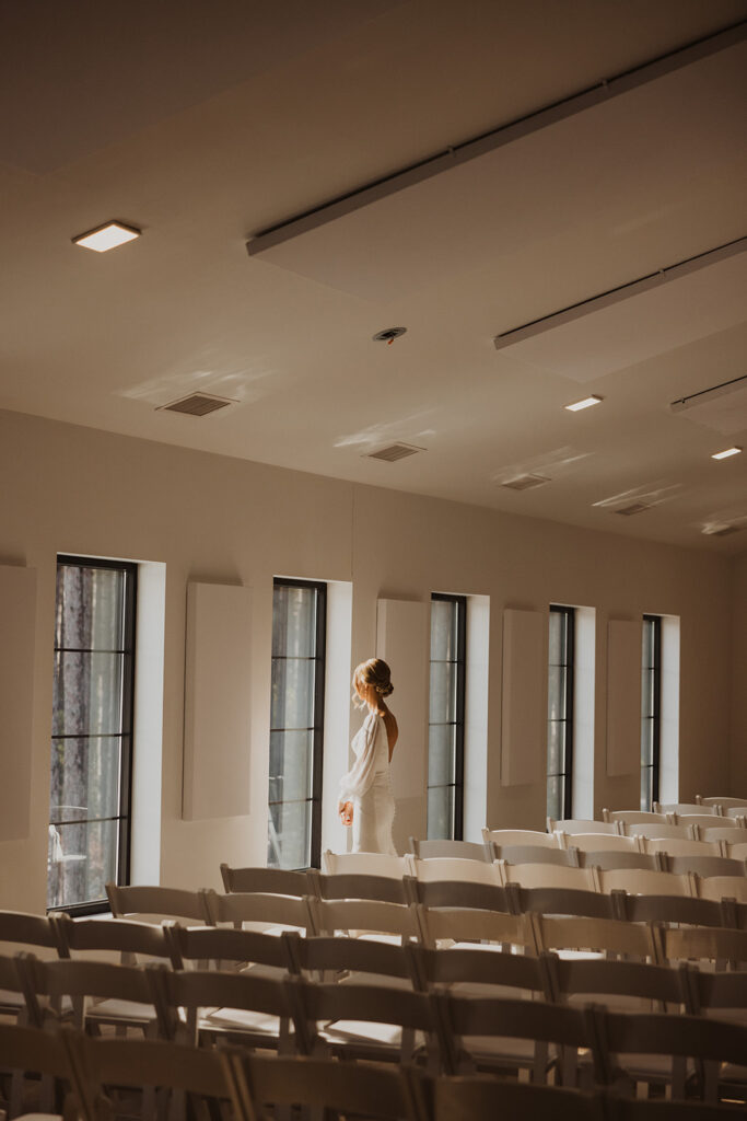 Bride looks out the window of winter wedding venue as she stands in dappled sunlight