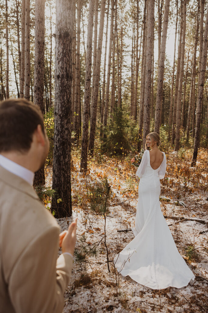 Bride shows off the back of her dress as groom celebrates how beautiful she looks