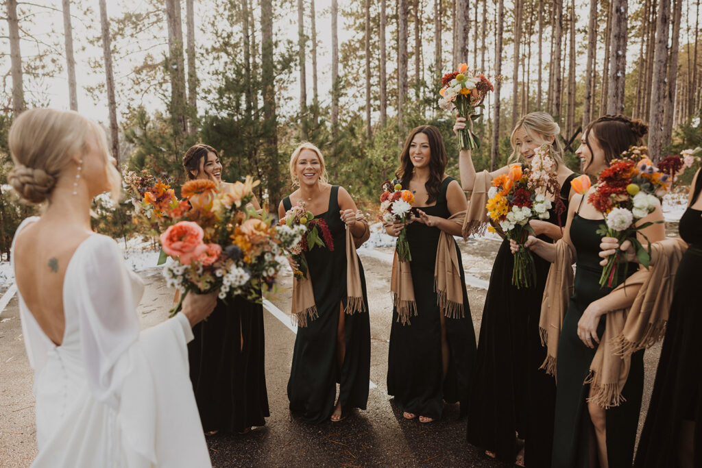 Bridesmaids and bride decompress under the pines at winter wedding venue in Minnesota