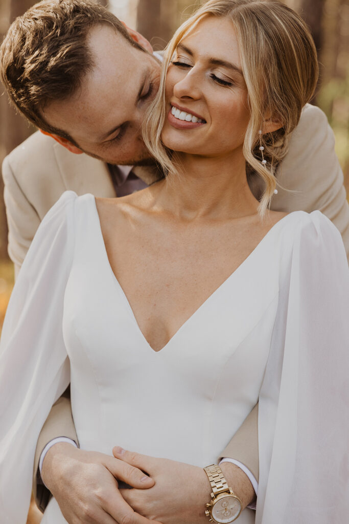 Groom kisses blonde bride from behind