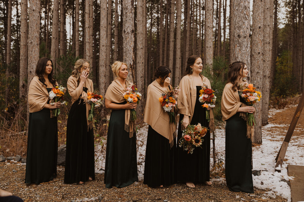 Emotional bridesmaids wipe their eyes as they watch the winter wedding ceremony in Minnesota