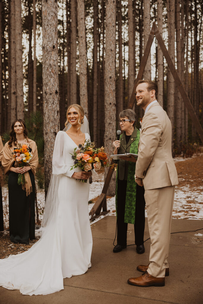 Bride and groom smile at all of their family and friends gathered at winter wedding venue for their I do's