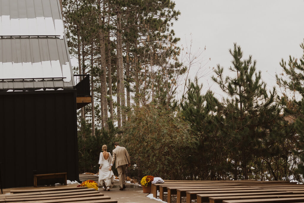 Groom carries bride's train as they walk into winter wedding venue in Minnesota