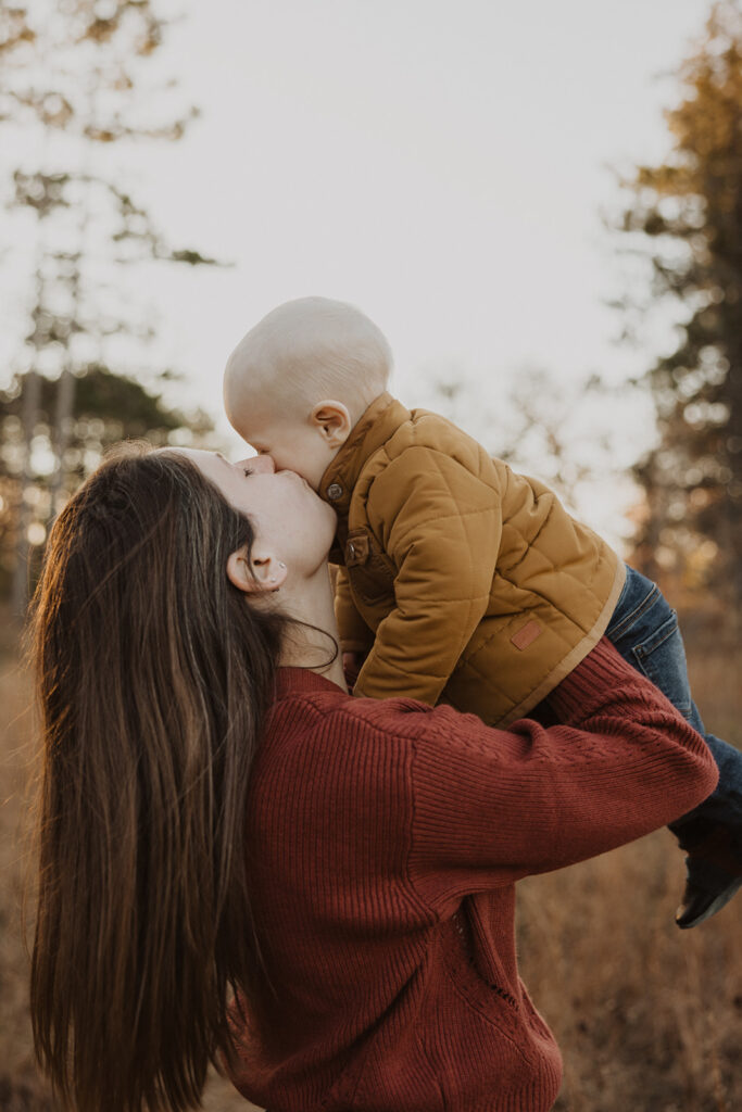 Mom holds baby up into the air and gives his cheek a kiss