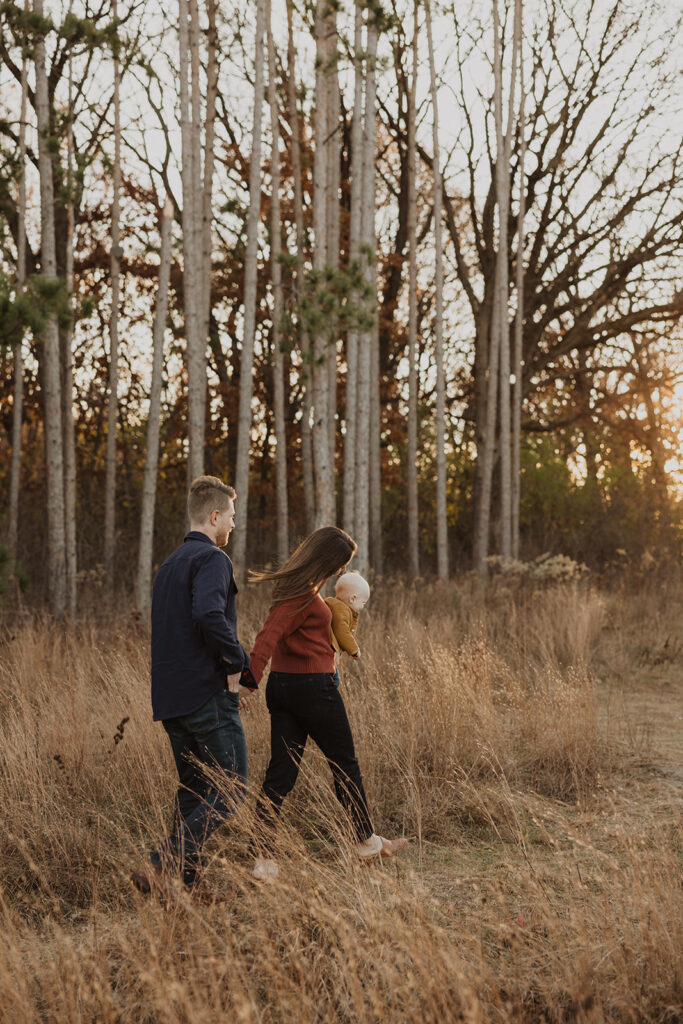 Young family walks through the brush of Minnesota field in autumn glow