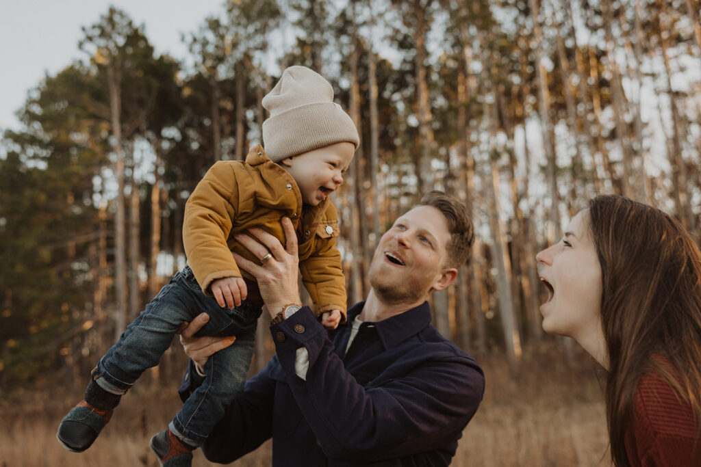 Dad plays airplane with baby as mom makes a funny face at him