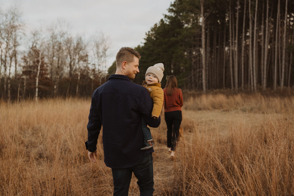 Young family walks off into the distance while baby looks over dad's shoulder