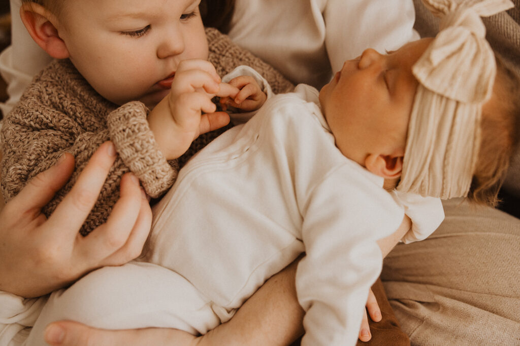 Young boy plays with his baby sister's fingers