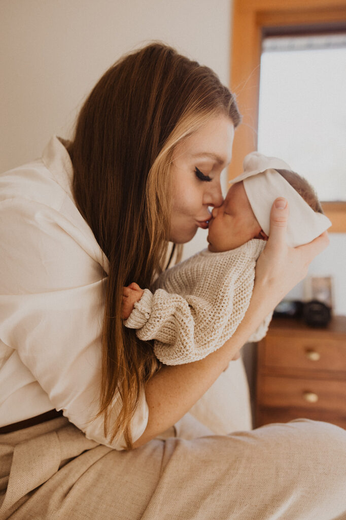 Mom kisses newborn baby's nose