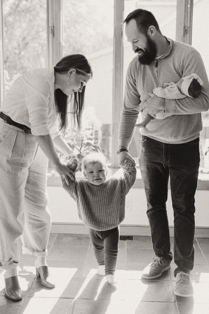 Parents walk hand in hand with toddler son in newborn photography with family