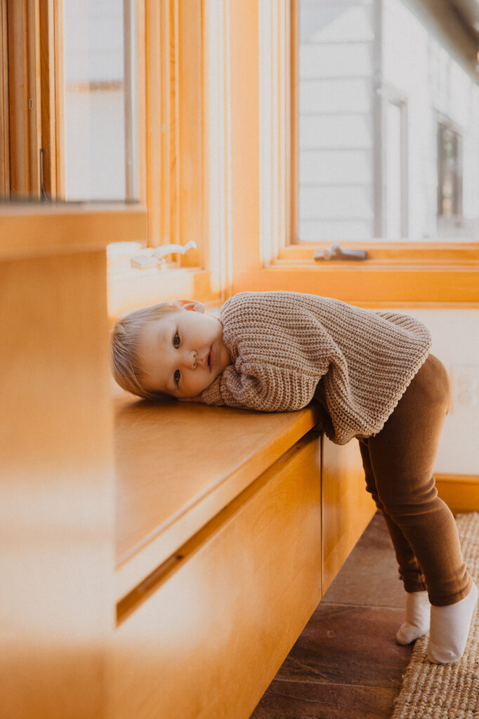 Toddler rests his head on mudroom bench