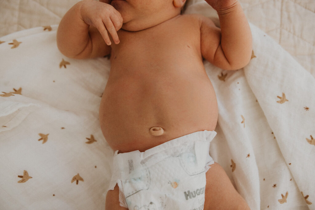 Bare baby tummy on muslin blanket in newborn photography with family